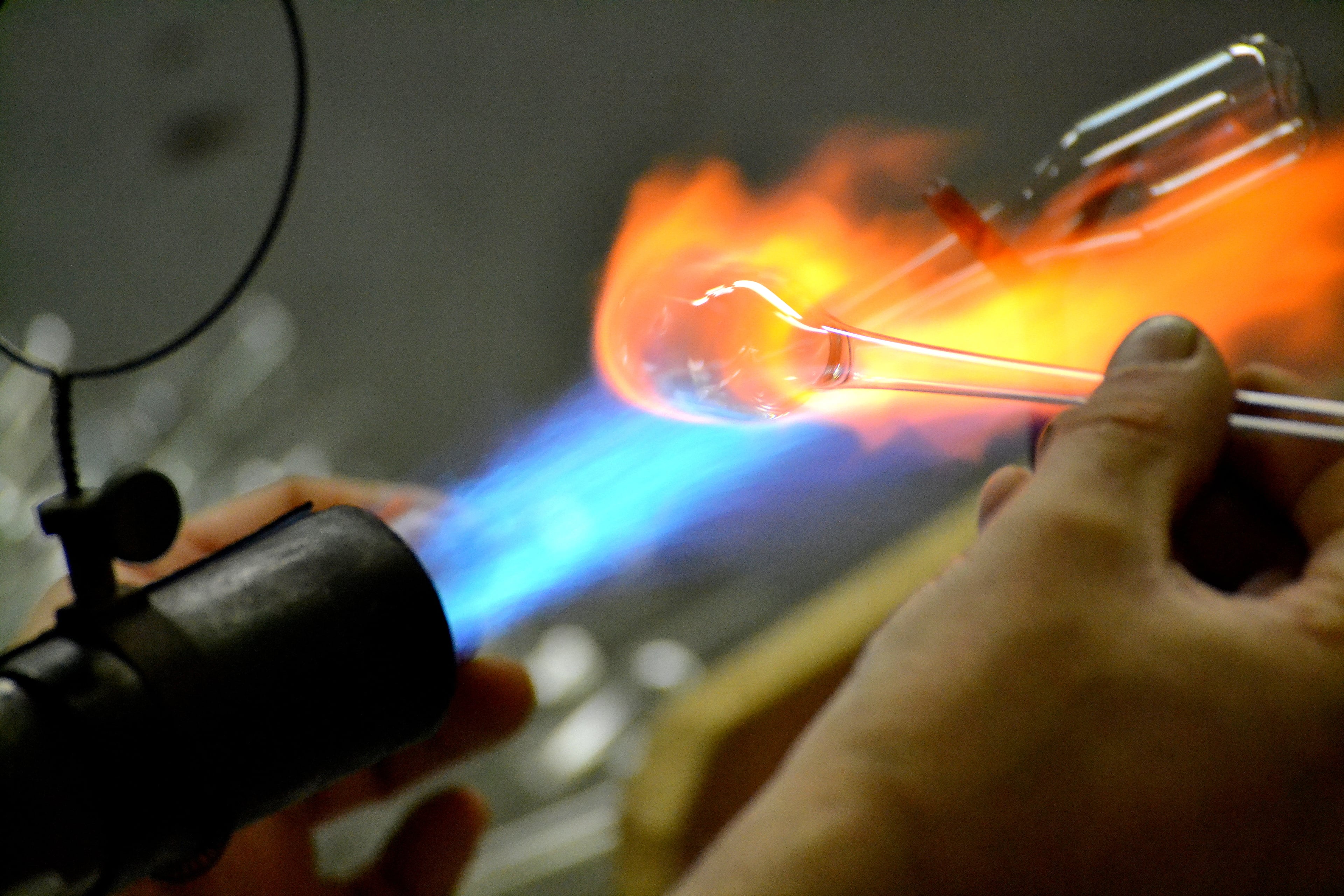 Sklář foukající skleněnou ozdobu v plameni